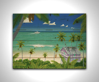 A vibrant painting of a lavender house with a stilt foundation built on a white sand beach. Lush island foliage surrounds it, including tall palms. The sea before it is calm and bright blue, and a white fishing boat sails in the distance. Printed on a wood pallet.