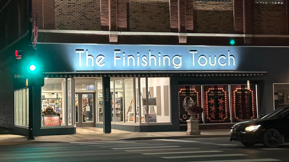 The front entrance of The Finishing Touch retail location, photographed at night. The store's name sign is lit from below against a blue wall.