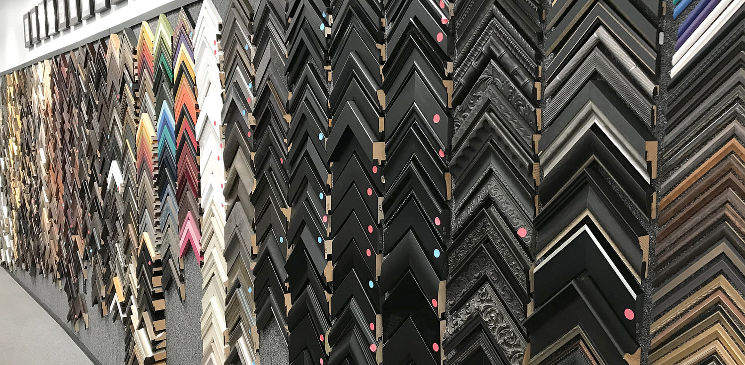 A wall covered in picture frame sample corners in various colors and designs.