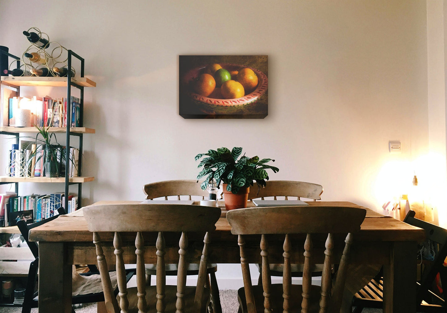 A cozy kitchen with solid wood furniture and gentle lighting. A canvas photograph of a bowl of fruit hangs on the wall.