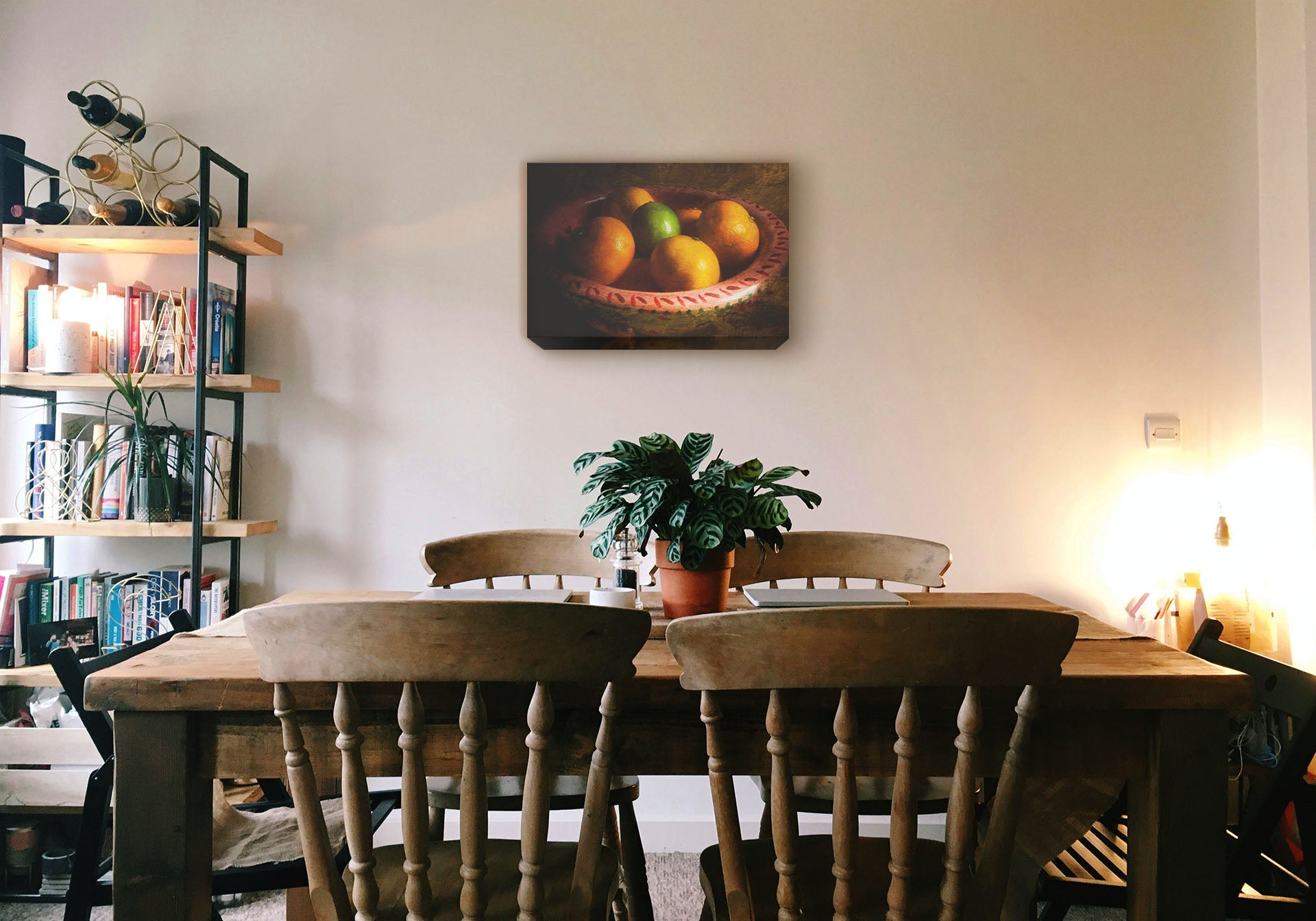 A cozy kitchen with solid wood furniture and gentle lighting. A canvas photograph of a bowl of fruit hangs on the wall.