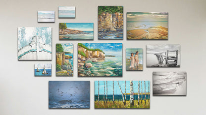 A collage of art in the standard Crystal Clear package, including three box board photos of beach views and sailboats; a box board painting of children on the beach; five canvas photos of the ocean in Scotland, a black and white pier, black and white rowboats, birds over the sea, and an old boat bow; and five canvas paintings of Artist's Point at Lake Superior in Minnesota, three seaside cliff faces, and a view of the sea from a birch copse.