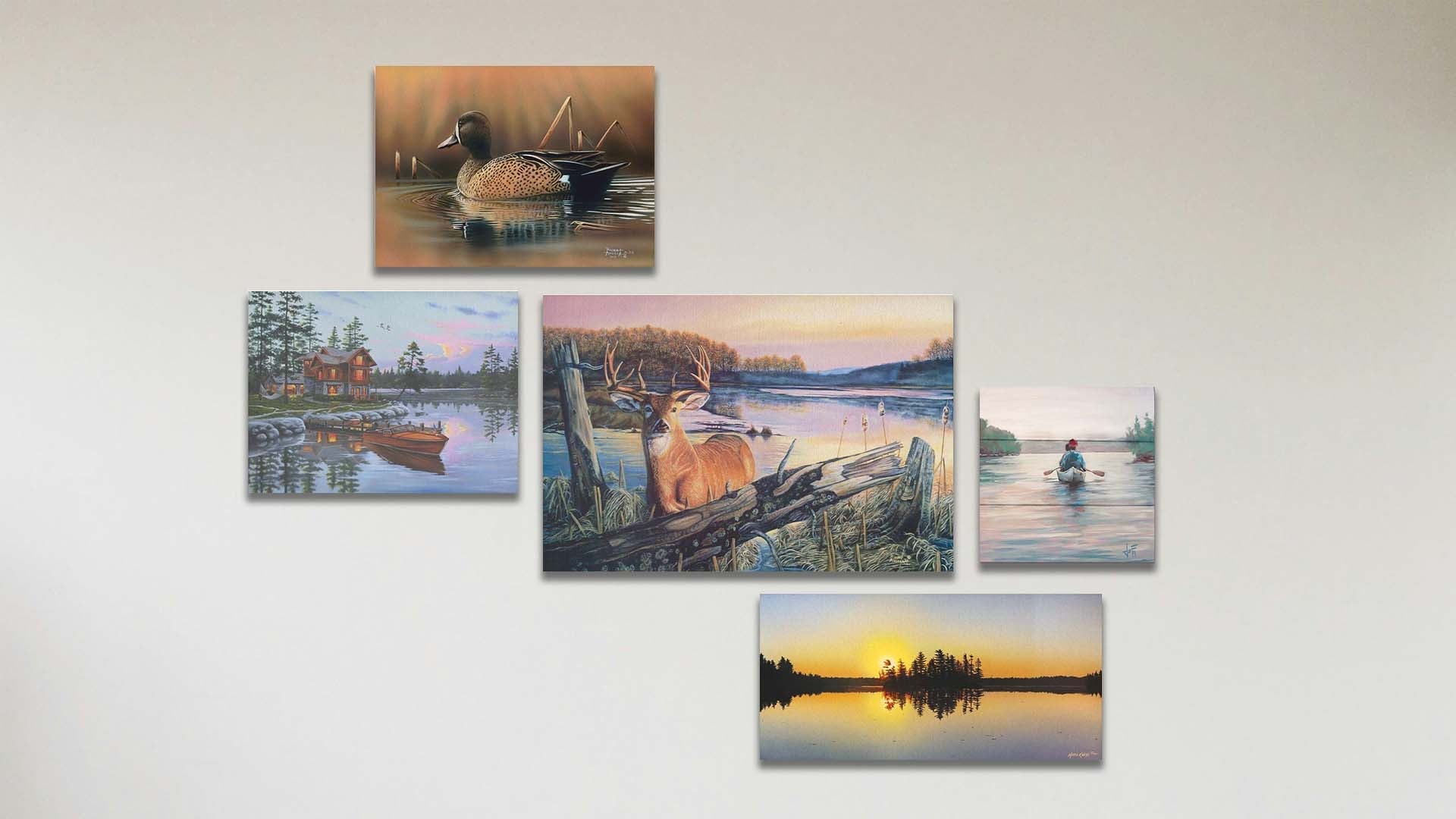 A collage of art in the standard By Dawn's Early Light package, including a canvas painting of a deer standing in a lake at sunrise, a canvas painting of a blue-winged teal swimming in a brown scene, a canvas painting of a lakeside cabin and docked rowboat, a canvas painting of a calm lake reflecting the low sun, and a box board painting of people paddling a canoe across a lake on a peaceful, misty morning.