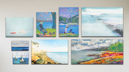 A collage of art in the standard Full Spectrum package, including a box board photo of sailboats on the ocean; a box board painting of an abstracted sea view; three canvas photos of an old jetty, homes on the seaside, and boats on a foggy sea; and three canvas paintings of a colorful shoreline, a person with ducks on a bench by the water, and a person with their dog sitting on the Seattle shoreline. 