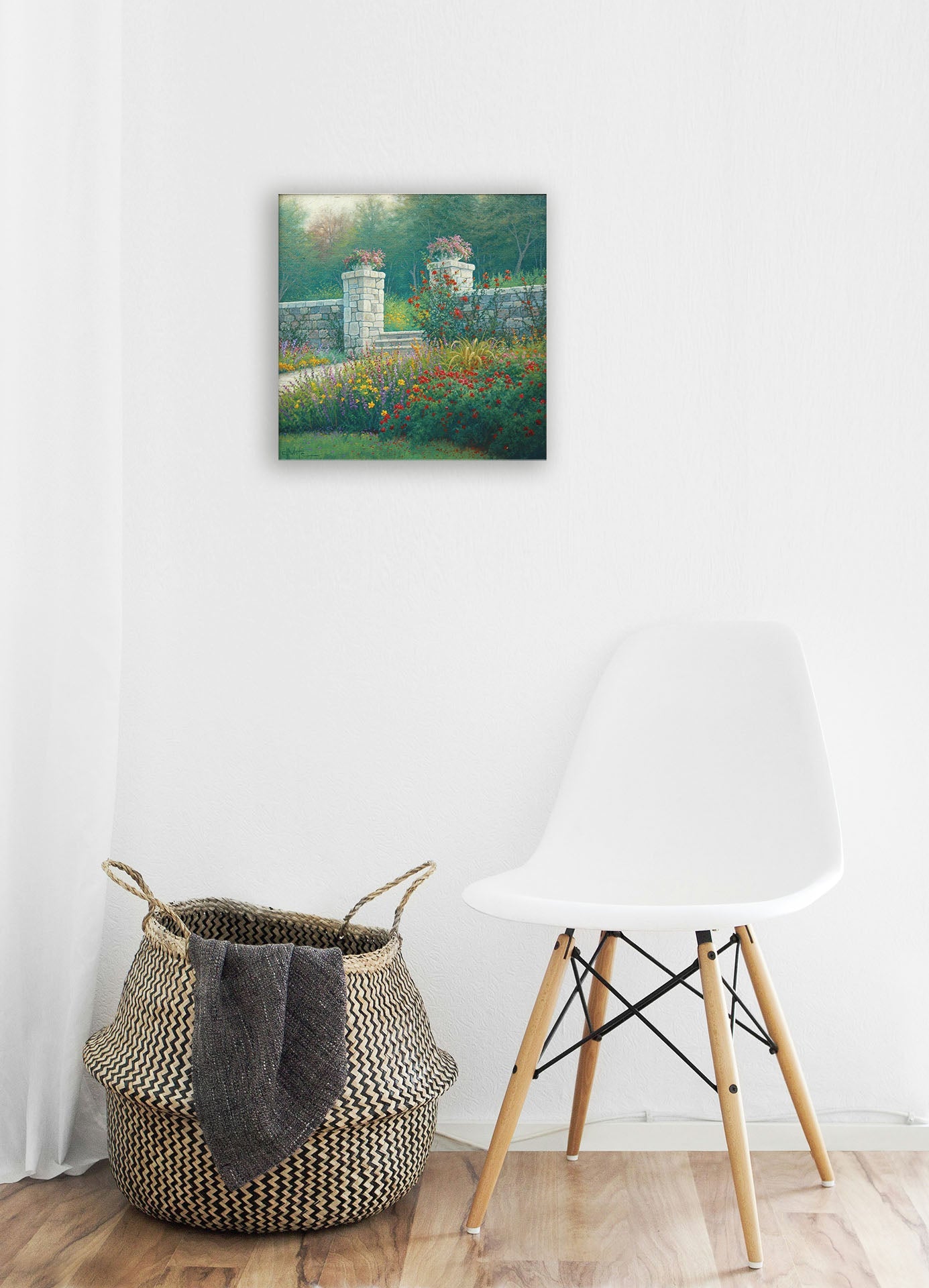 A white room with wood accents and a woven basket. A canvas painting of a walled garden hangs on the wall.