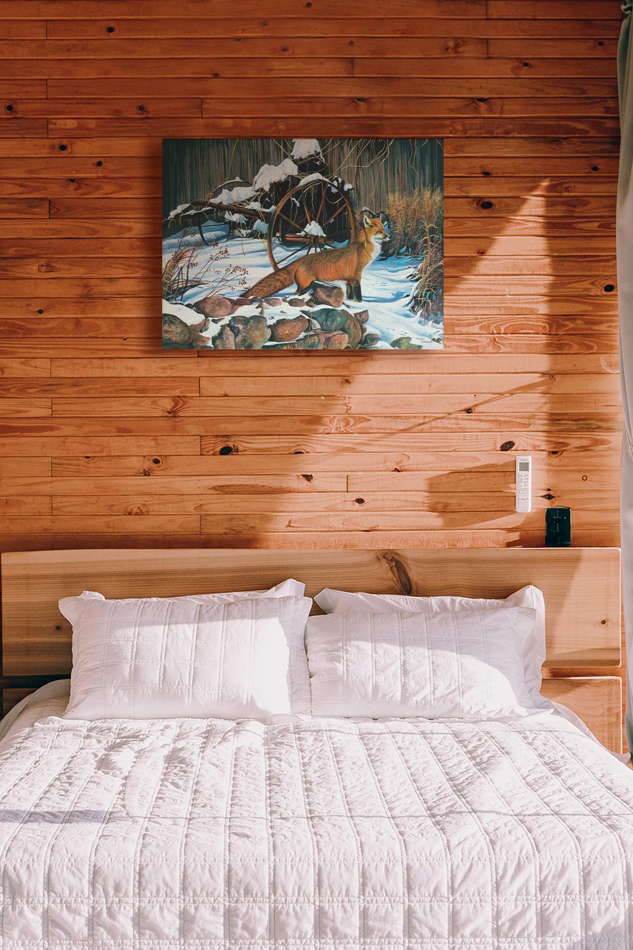 A painting hanging on a bedroom wall. A painting of a red fox in the winter snow. It is standing by some old farming equipment, grasses, and stones. Printed on canvas.