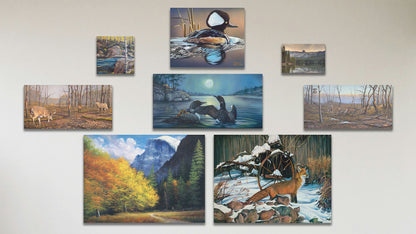 A collage of art in the standard Hiking to Half Dome package, including seven canvas paintings of a hooded merganser duck, a family of loons swimming on a moonlit lake, a red fox standing on alert in the snow, a wooded trail at the Half Dome batholith at Yosemite National Park in California, a fight between two deer bucks, and deer trekking through wintery woods; a box board painting of a stream through a birch forest; and a box board photo of Lake Mamie in California.