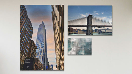 A collage of art in the standard Empire State Building package, including a box board photograph of a rainy city, a canvas photograph of the Empire State Building in New York City, and a canvas photograph of the Brooklyn Bridge in New York City.