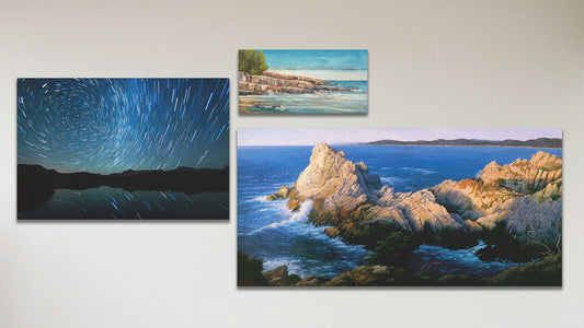 A collage of art in the standard Pinnacle at Sunset package, including a canvas long-exposure photograph of the stars reflecting off Mirror Lake in Utah, a canvas painting of the cliffs at Cypress Grove Trail Point Lobos in California, and a box board painting of Artist's Point Lake Superior in Minnesota.