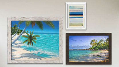 A collage of art in the designer Barefoot Beach package, including a framed painting of a vibrant tropical beach, a framed photograph of Laniākea beach (nicknamed Turtle Beach) on Oʻahu, Hawaiʻi, and a matted and framed abstract geometric painting invoking boats, the shore, and sea.