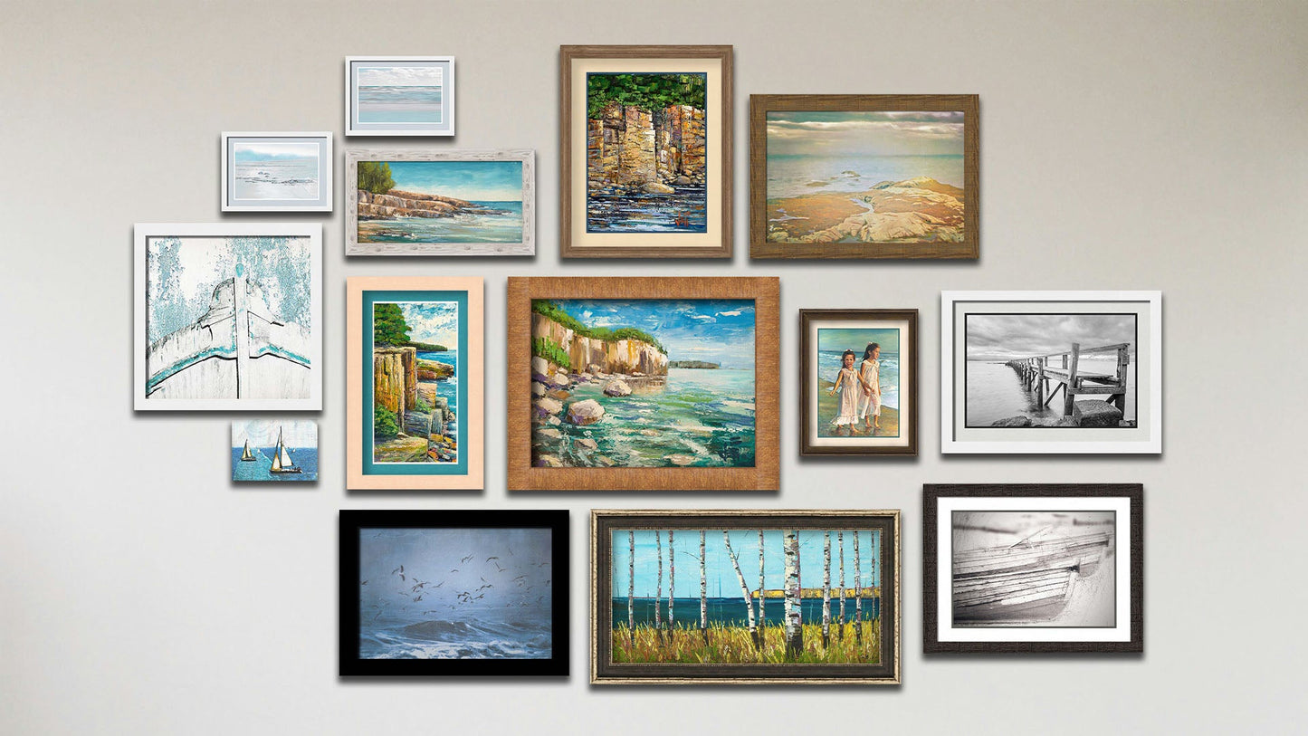 A collage of art in the designer Crystal Clear package, including a canvas photo of sailboats; three framed photos of an old boat bow, birds over the sea, and the sea from Scotland; three framed paintings of Artist's Point at Lake Superior in Minnesota, a view of the sea from a birch copse, and a seaside cliff face; two framed photos of a beach view; two framed photos of a black and white pier and rowboats; and three matted and framed paintings of a cliff face and of children on the beach.