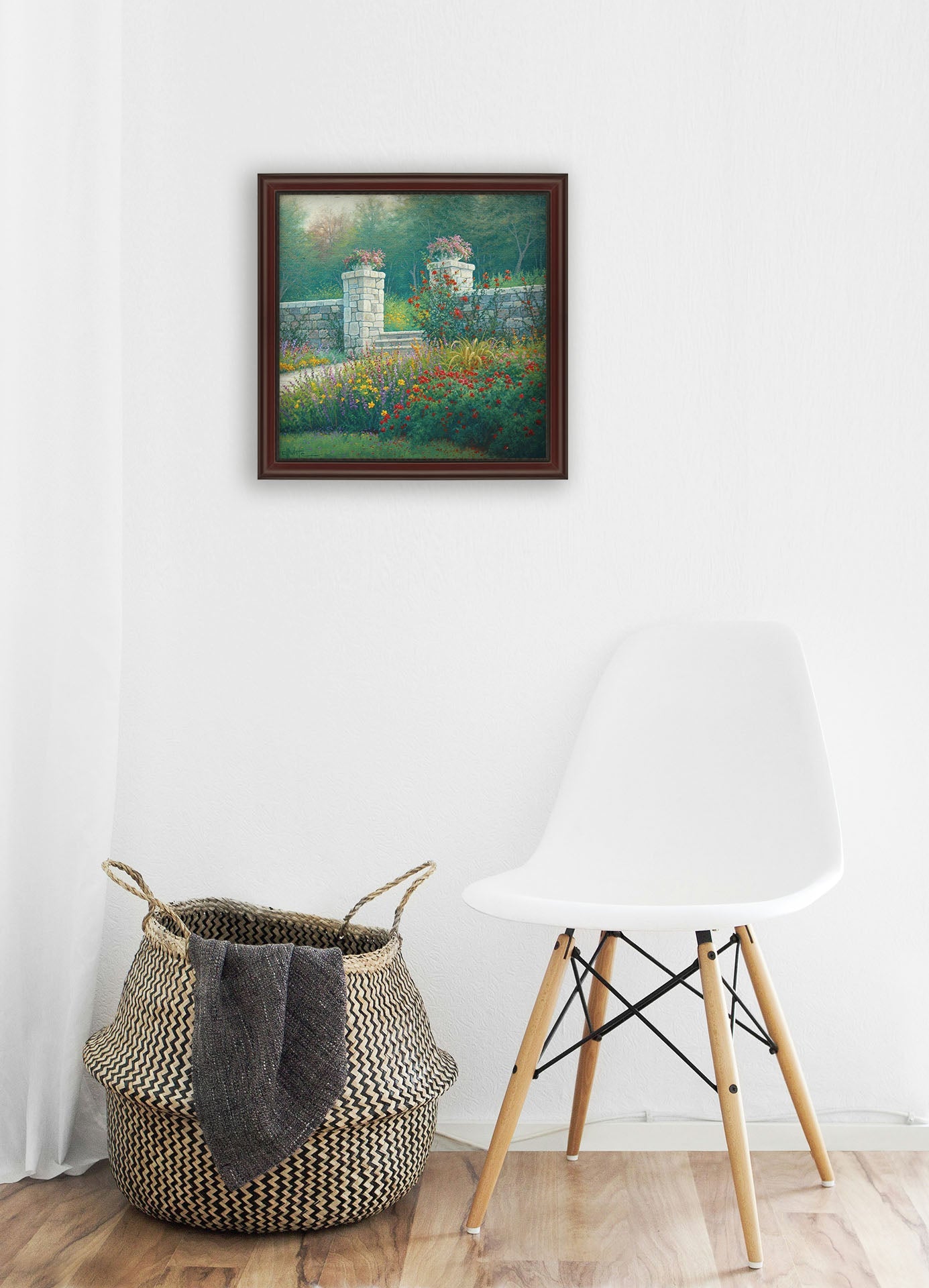 A white room with wood accents and a woven basket. A framed painting of a walled garden hangs on the wall.