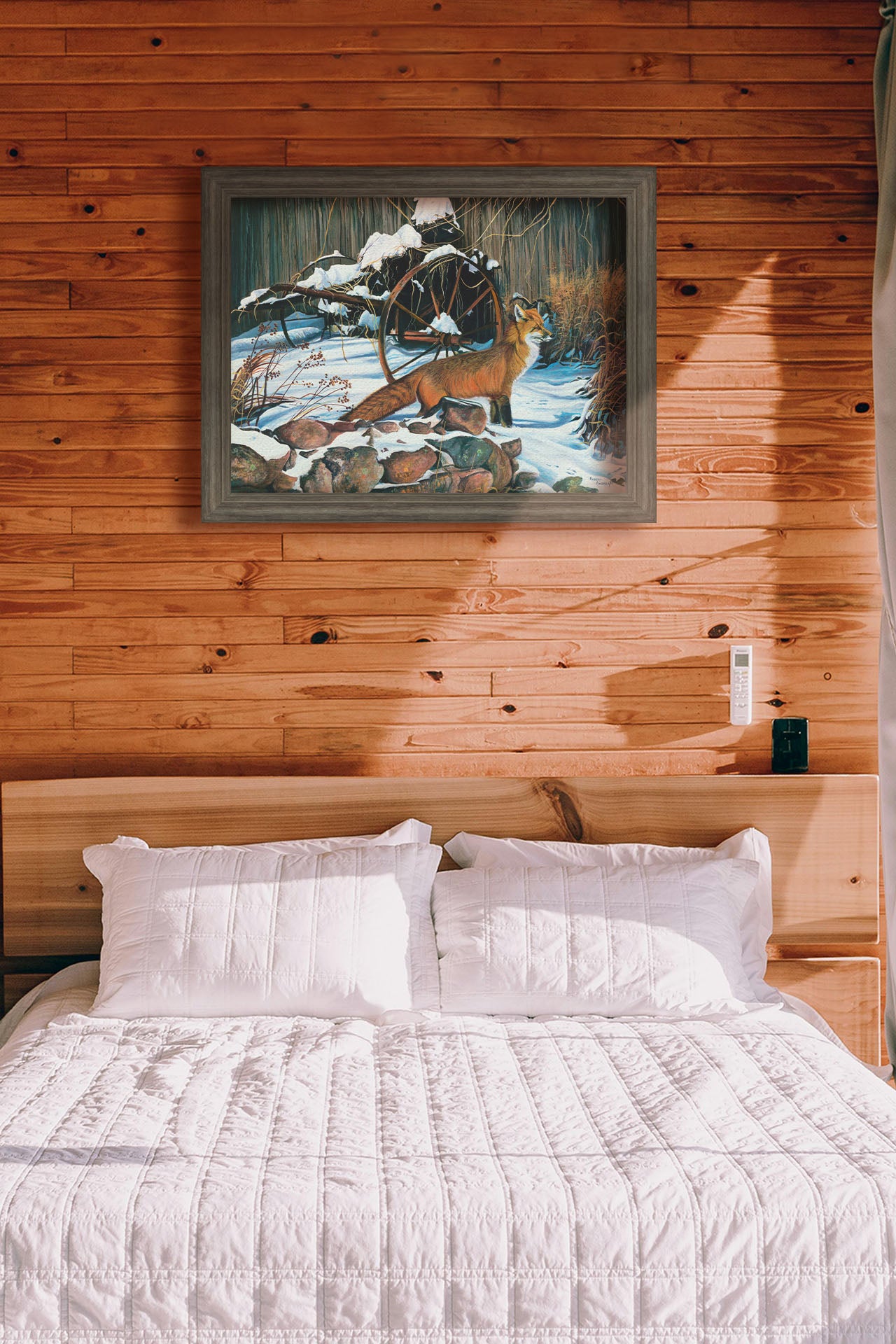 A painting hanging on a bedroom wall. A painting of a red fox in the winter snow. It is standing by some old farming equipment, grasses, and stones. Printed on canvas and framed.