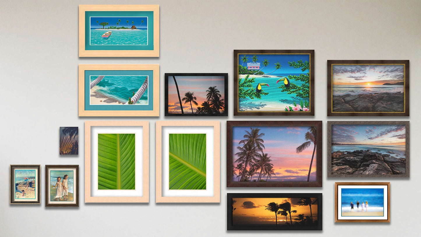 A collage of art in the designer Pastel Palms package, including two matted and framed paintings of kids on the beach; two framed photos of palm trees; a matted and framed photo of kids on the beach; a canvas photo of tropical plants at sunset; two float framed paintings of an island beach and a rowboat at an island; a framed painting of toucans perched on beach plants; two framed photos of Manly Beach, Australia; two framed photos of bird of paradise palms; and a framed photo of a sunset in Maui.