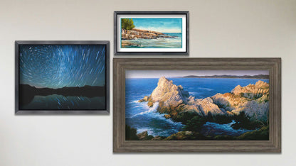 A collage of art in the designer Pinnacle at Sunset package, including a framed long-exposure photograph of the stars reflecting off Mirror Lake in Utah, a framed painting of the cliffs at Cypress Grove Trail Point Lobos in California, and a matted and framed painting of Artist's Point Lake Superior in Minnesota.