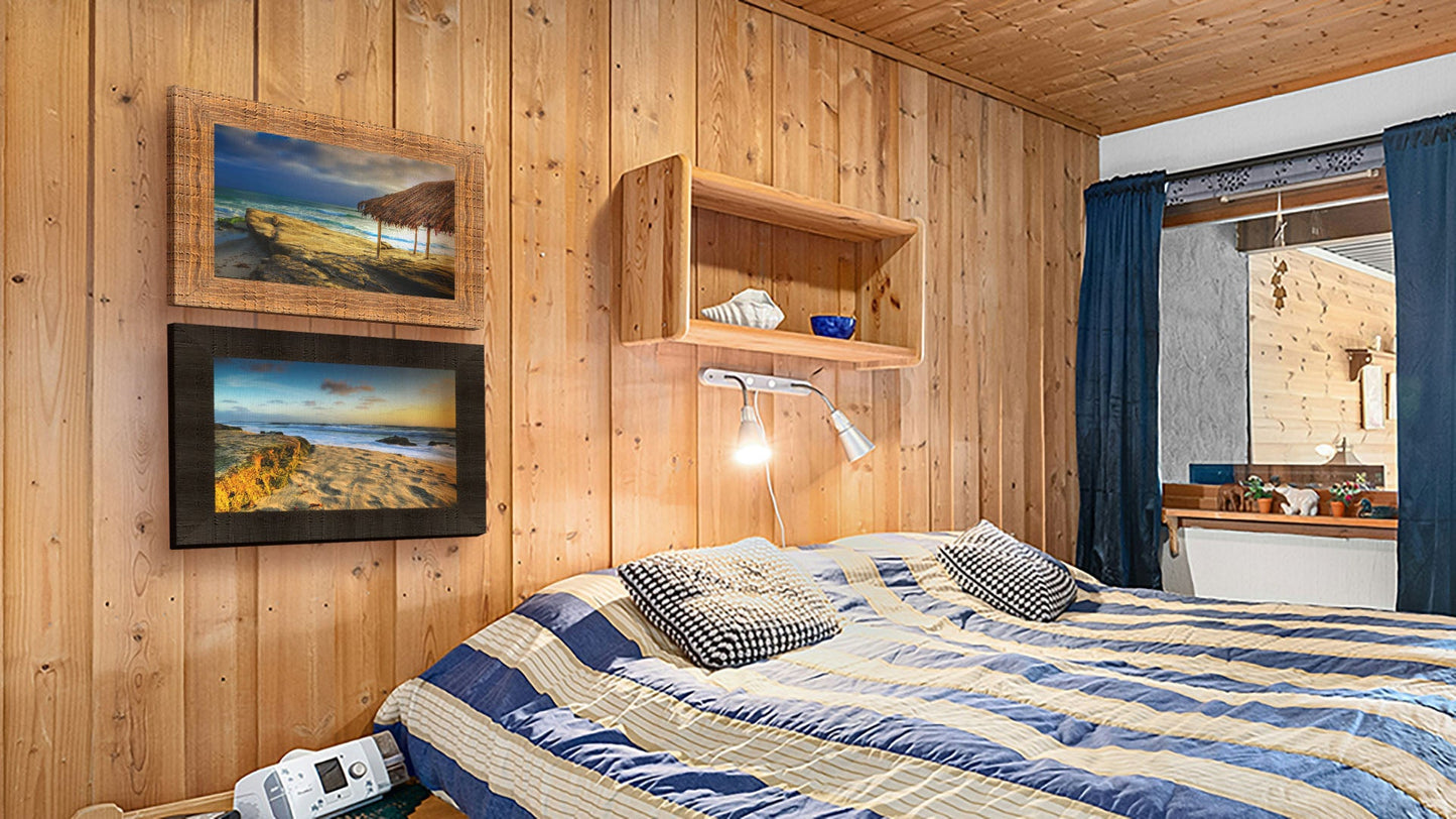 A seaside bedroom with light wood walls and blue and white furniture. Two framed photographs of Windansea Beach hang on the wall.