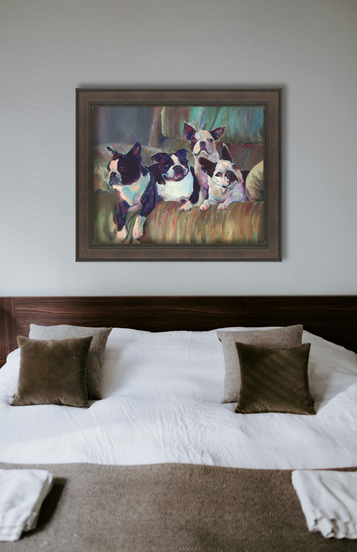 A painting hanging on a bedroom wall. A painting of four Boston terriers, posed lying in a light brown armchair. Printed on canvas in a float frame.