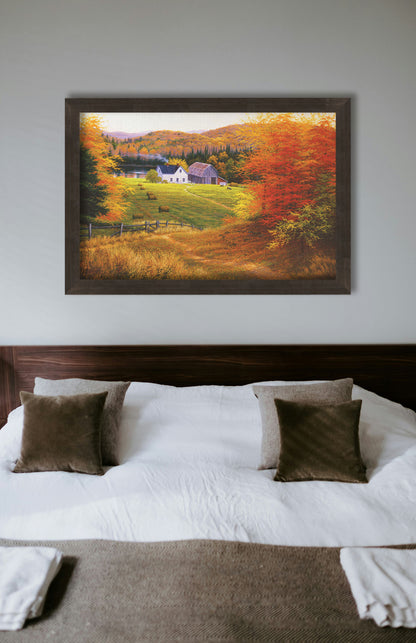 A painting hanging on a bedroom wall. A painting of a view looking down on a lakeside home and barn from a forest, featuring a few farm animals and hay bales. Printed on canvas and framed.