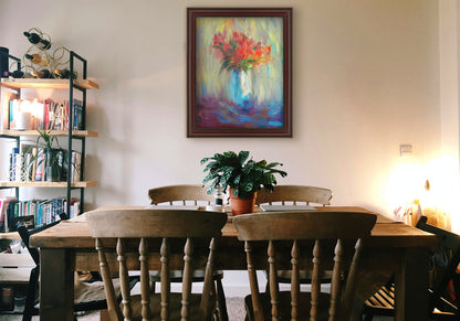 A painting hanging on a dining room wall. A still life painting of a vase of bright red flowers, created with expressive visible brushstrokes and broken color. Printed on canvas and framed