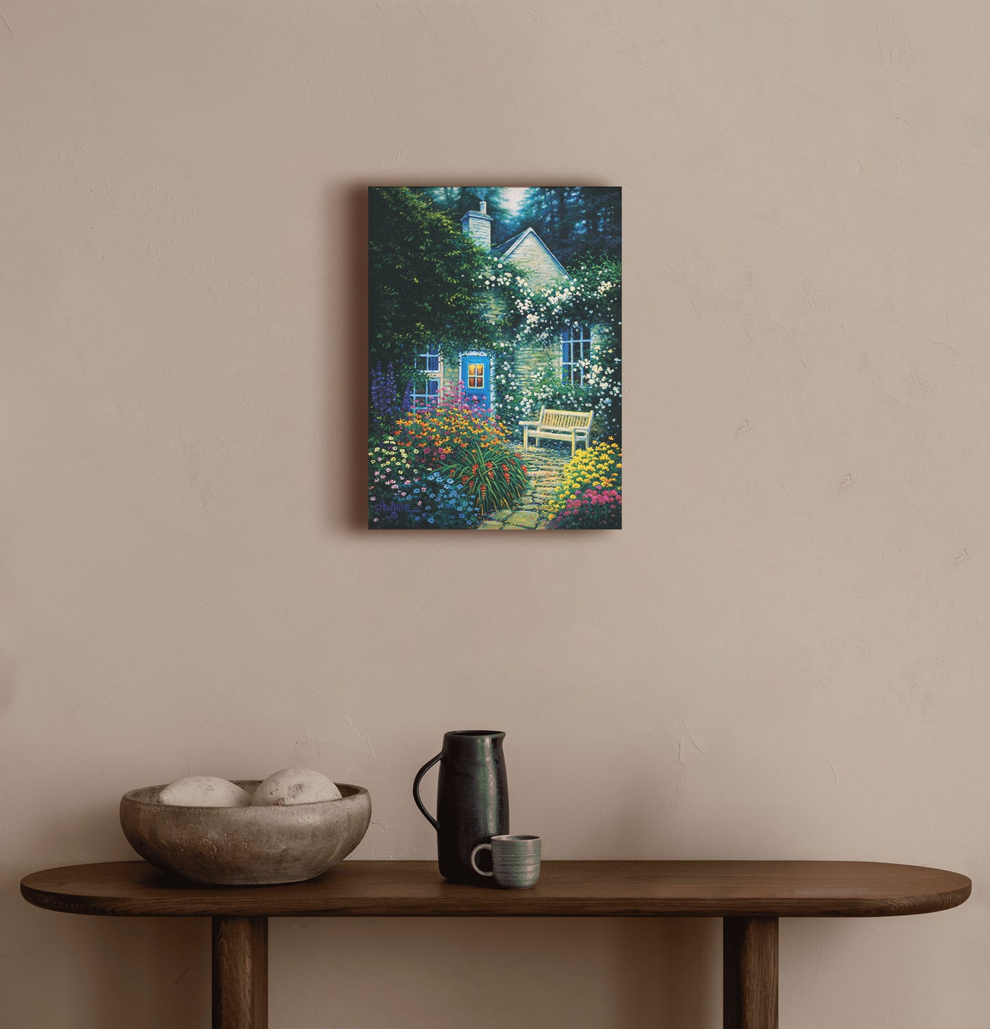 A painting hanging on a hallway wall. A painting of a cottage and stone path with a bench, all surrounded by colorful flower bushes and vines. Printed on canvas.