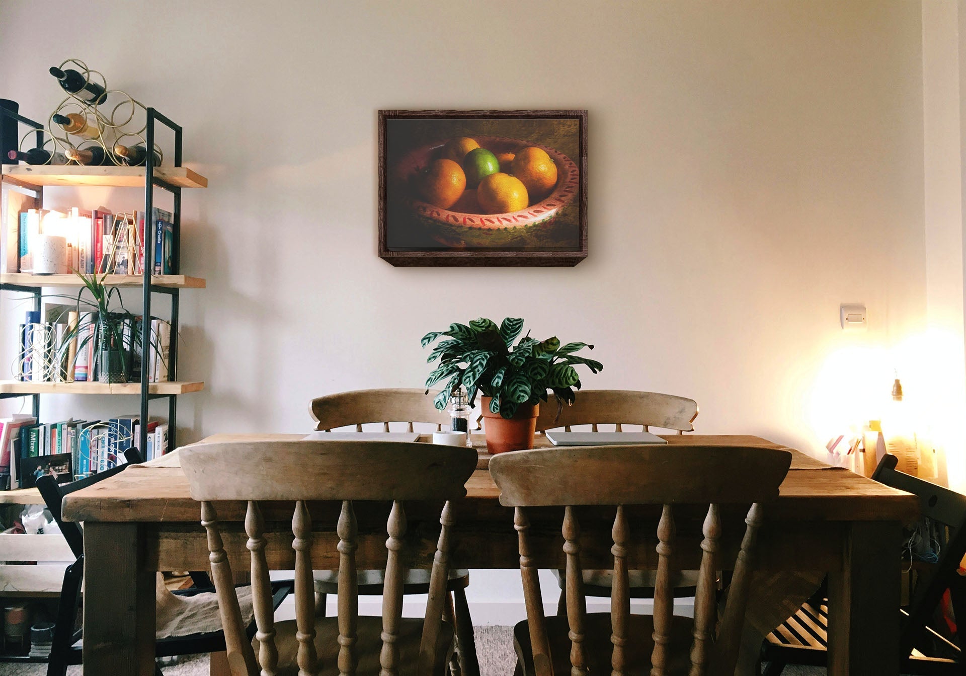 A cozy kitchen with solid wood furniture and gentle lighting. A float framed photograph of a bowl of fruit hangs on the wall.