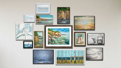 A collage of art in the luxury Crystal Clear package, including five float framed photos of the ocean in Scotland, a black and white pier, black and white rowboats, birds over the sea, and an old boat bow; four float framed paintings of Artist's Point at Lake Superior in Minnesota, two seaside cliff faces, and a view of the sea from a birch copse; a framed photo of sailboats; two matted and framed photos of a beach view; and two matted and framed paintings of a seaside cliff and children on the beach.