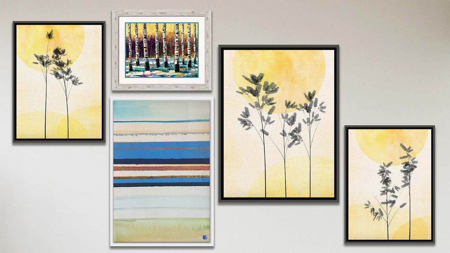 A collage of art in the luxury Feeling Love package, including a series of three float framed photos of plants silhouetted against yellow skies, a float framed abstract geometric painting invoking boats and the shore, and a matted and framed painting of birch trees in winter against a yellow sky.