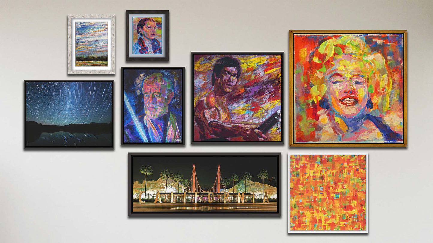 A collage of art in the luxury film package, including two matted and framed paintings of a wide open sky and Judy Garland as Dorothy in The Wizard of Oz; two float framed photographs of the California Adventure sign and the stars over Mirror Lake; and four float frame paintings of Alec Guinness as Obi-Wan Kenobi in Star Wars, Marilyn Monroe, Bruce Lee, and an abstract colorful contemporary pattern.