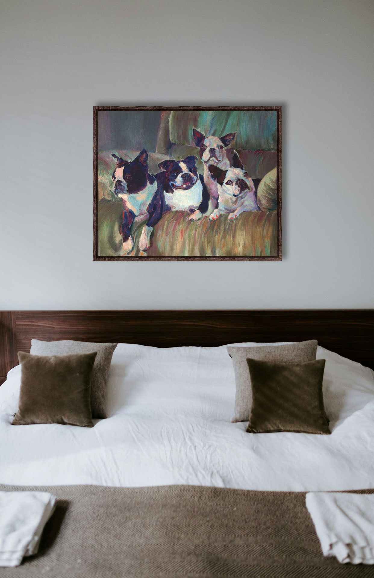 A painting hanging on a bedroom wall. A painting of four Boston terriers, posed lying in a light brown armchair. Printed on canvas in a float frame.