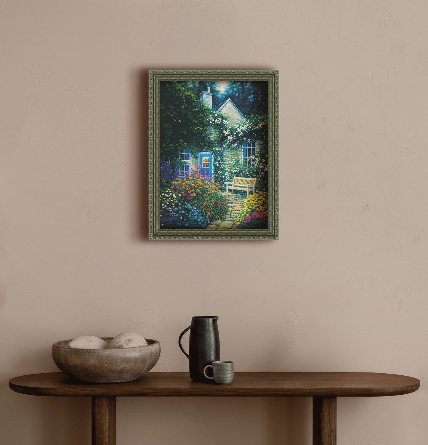 A painting hanging on a hallway wall. A painting of a cottage and stone path with a bench, all surrounded by colorful flower bushes and vines. Printed on canvas and framed.