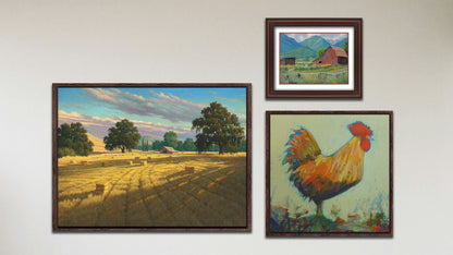 A collage of art in the luxury Sunset Hayfield package, including a matted and framed painting of a barn in the mountains, a float framed painting of an orange rooster, and a float framed painting of a hayfield at sunset.