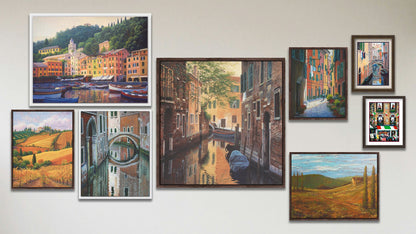 A collage of art in the luxury Venetian Back Alley package, including a matted and framed painting of an Italian community, a matted and framed painting of clothes hanging over a canal in Italy, and eight float framed paintings of a streetlight over an alley, a field in Tuscany, a canal alleyway in Venice, a bridge reflecting on the waters of a canal, colorful vineyards in Tuscany, and a painting of boats docked in the city of Portofino.